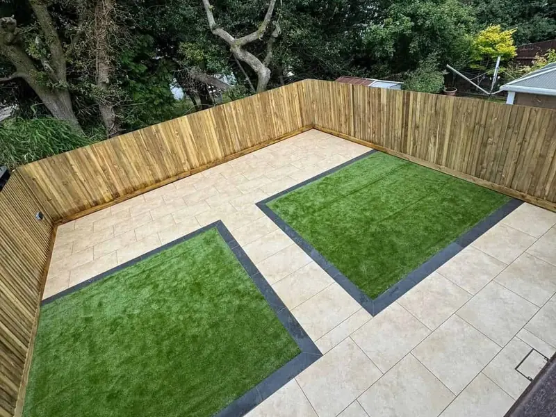 Two rectangles of artificial grass set into a pale porcelain patio and edged with dark paving