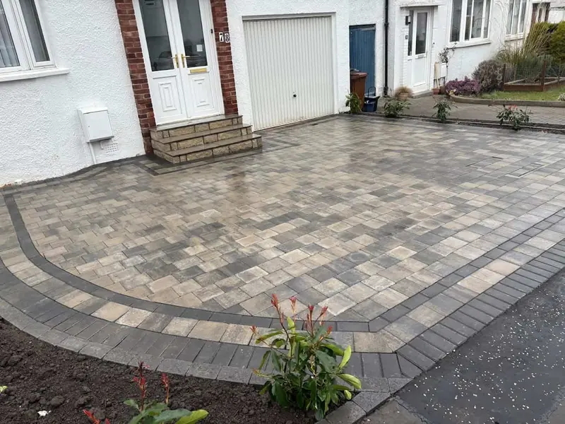 Block paved front driveway with a charcoal border in front of a white rendered semi-detached house