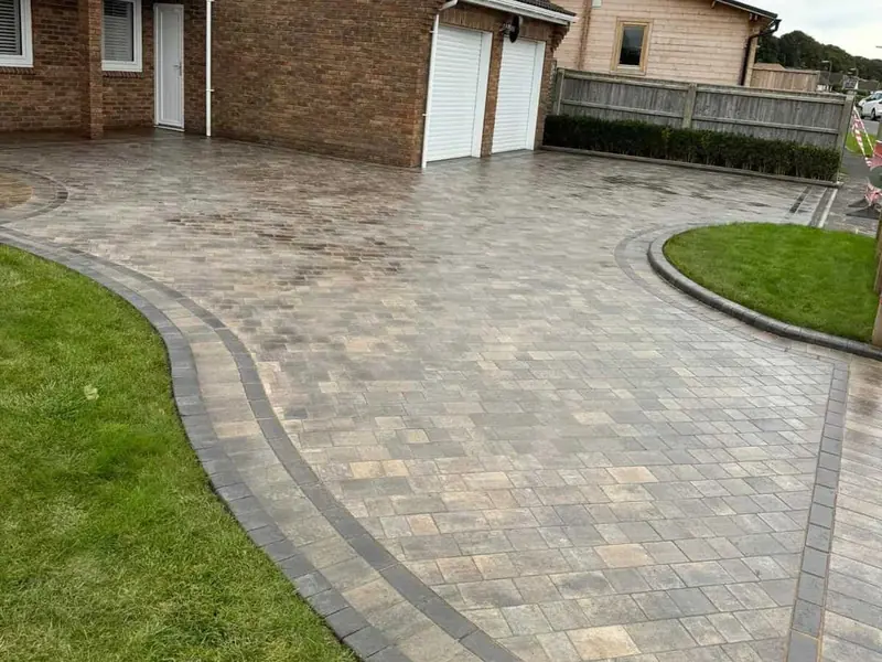 Curved block paved driveway with a charcoal border running beside a lawn
