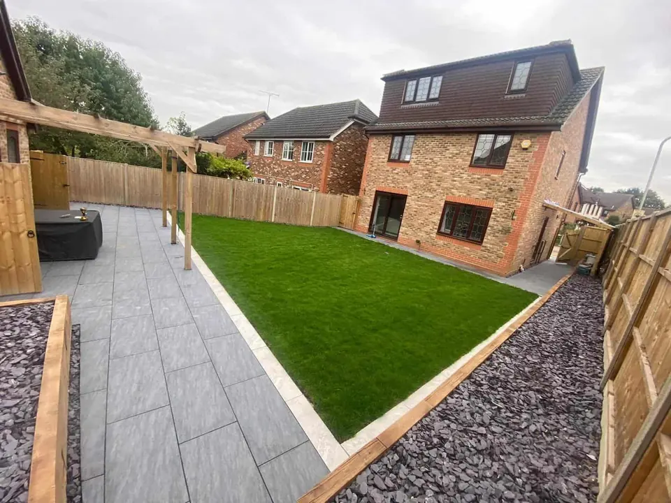 Landscaped back garden with a grey porcelain path, new lawn, slate chipping borders and a timber pergola