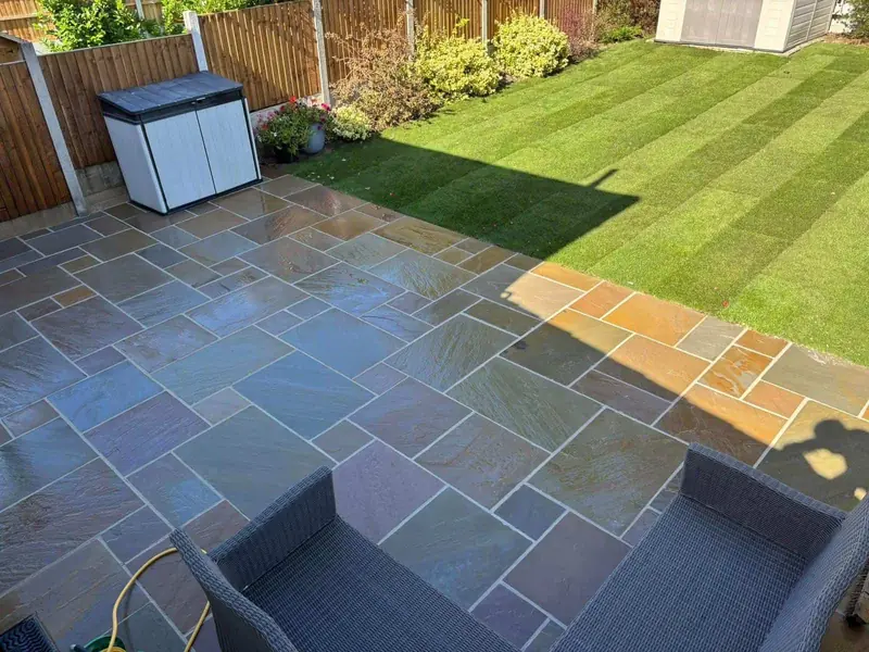 Freshly laid striped turf lawn beside an Indian sandstone patio with garden chairs