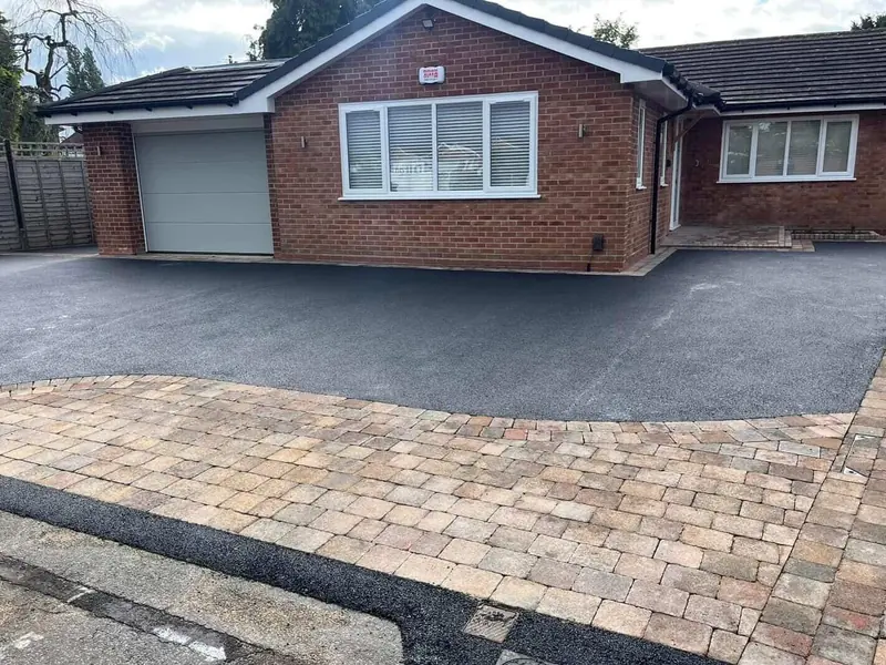 Tarmac driveway with a brindle block paving border in front of a brick bungalow